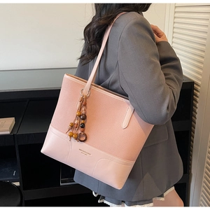 Dettaglio borsa shopper rosa con tessuti combinati, nappine di legno e stampa logo