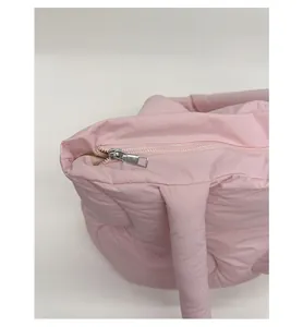 Close-up of a smooth silver zipper on a pink quilted puffer handbag with soft padding
