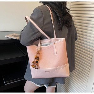 Borsa tote rosa in ecopelle con ciondolo in perle di legno indossata da una modella
