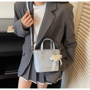 Dettaglio mini borsa a secchiello azzurra con ciondolo a cuore e fiocco di pizzo