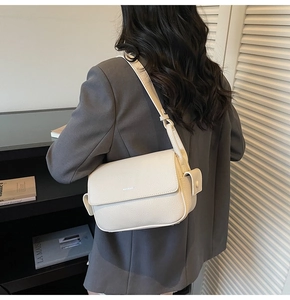 Detail showing the white pebble leather texture and embossed logo on this square handbag