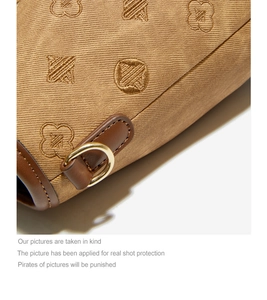 Macro detail of brown clover embroidery and gold metal D-ring on bucket bag