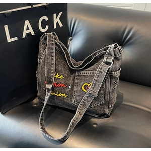 Close-up of embroidered denim tote bag with Like Fashion text on leather sofa