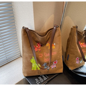 Detailed embroidery of colorful cartoon animals on a brown canvas tote with leather handles