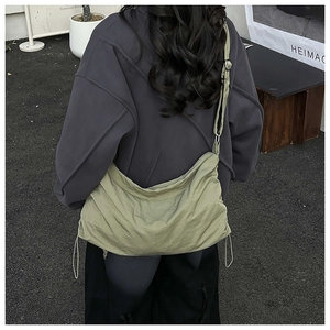 Détail du grand sac bandoulière en nylon vert sauge avec texture froissée et cordon latéral