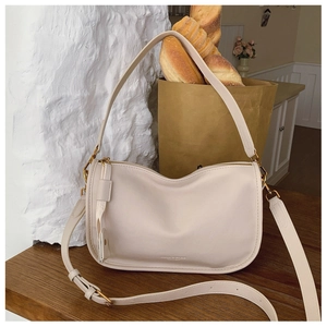 Close-up of beige shoulder bag featuring embossed Fashion & Bags text and gold hardware