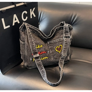 Macro view of washed denim tote with vibrant heart embroidery and side pocket detail