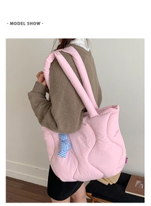 Detail of pink quilted tote bag with padded shoulder straps and checkered ribbon charm