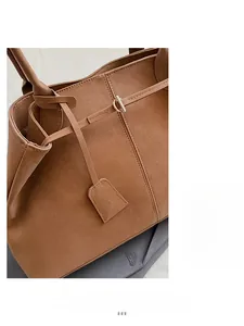 Détail d'un sac cabas en cuir marron souple avec coutures fines et boucle en D métallique