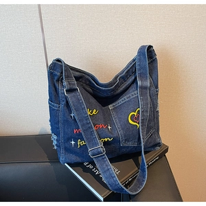 Detail view of navy denim tote bag with colorful embroidery and distressed edge texture