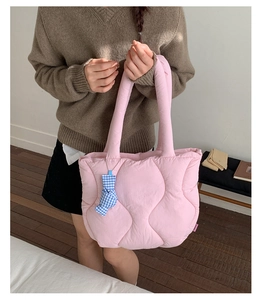 Detailed texture of pink quilted tote bag with cute blue checkered bow decoration