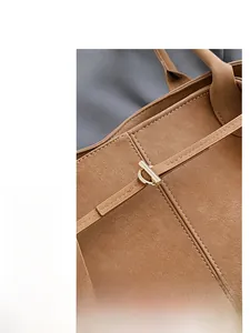 Gros plan sur la texture du cuir mat marron et le fermoir en métal doré du sac fourre-tout