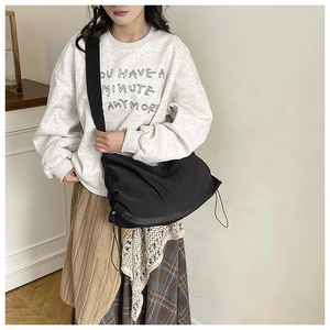 Gros plan du sac en nylon noir léger avec bandoulière large et fermeture à cordon