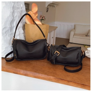 Detail of matte black leather bags with elegant pleated design and gold metal hardware
