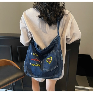 Close-up of heart embroidery and letters on a large capacity blue denim tote bag