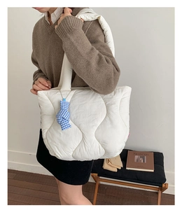 Detail of white quilted puffy tote bag with light nylon texture and blue checkered pendant