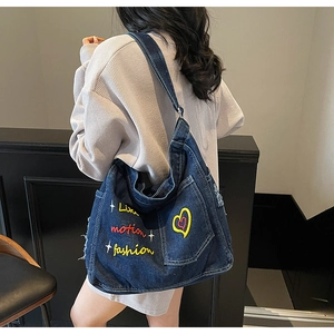 Detail of dark blue denim crossbody bag with colorful heart and letter embroidery