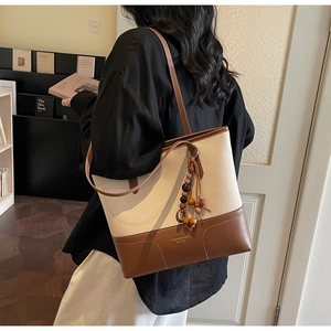 Vista dettagliata della borsa tote in tela con finiture in pelle e nappina in legno