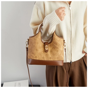 Detail view of vintage brown suede bucket bag with geometric patterns and golden metal clasp