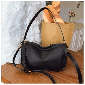 Detail of black leather crescent bag with vintage gold hardware in a French aesthetic setting