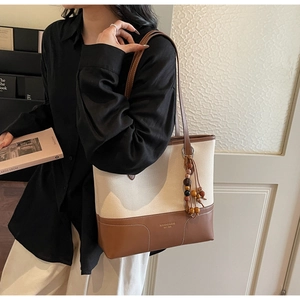 Dettaglio della borsa tote in tela con base in pelle marrone e nappa di perline in legno