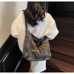 Detail of large denim tote bag with colorful embroidery and distressed ripped texture