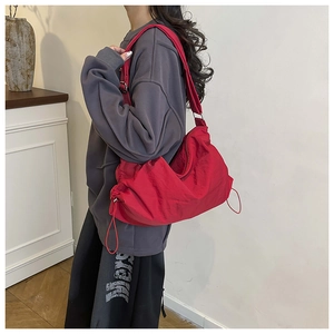 Vue détaillée du sac besace rouge en nylon montrant le cordon de serrage et la forme ample