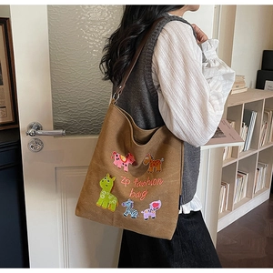Detail of a brown canvas tote bag featuring animal embroidery and brown leather straps