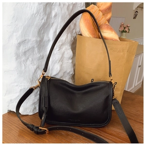 Detailed macro view of black soft leather texture and golden zipper on shoulder bag