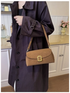 Detail of a brown vintage baguette bag with matte finish and gold metal buckle
