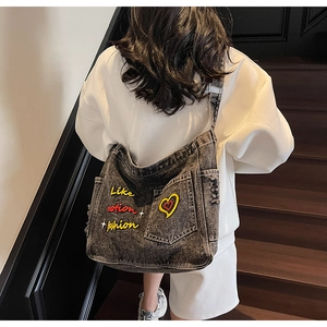 Detail of embroidered Like Motion Fashion text and heart on washed denim tote bag