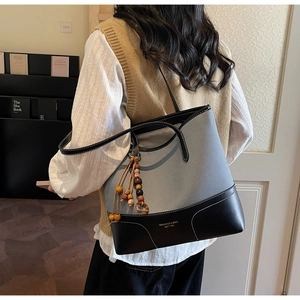 Dettaglio della borsa tote in tela grigia con finiture in pelle nera e nappa di perline