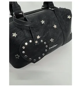 Detail of black vintage leather bag with silver star rivets and rhinestone heart charm