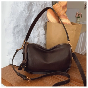 Close-up of a dark brown half-moon shoulder bag with golden zipper and oil-wax leather texture
