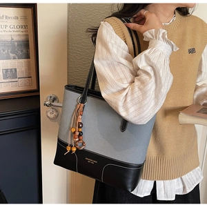 Dettaglio della borsa tote in tessuto grigio e pelle nera con ciondolo e logo