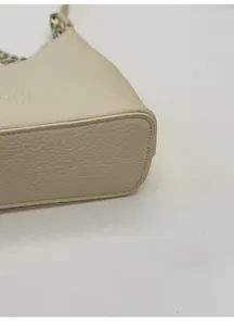 Detail einer beigen Handtasche aus genarbtem Leder mit breitem, strukturiertem Boden
