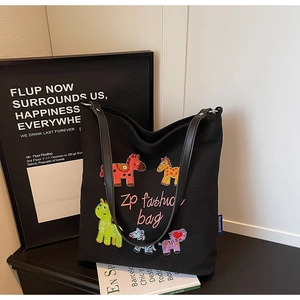 Detail of colorful animal embroidery on black canvas tote bag with leather straps