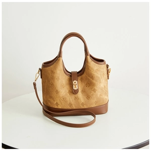 Close-up of brown bucket bag with embossed patterns, leather handle and metal lock
