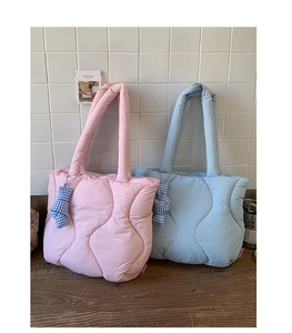 Quilted ripple tote bags in pink and blue with bow charms on a wooden surface