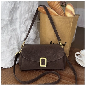 Nahaufnahme einer braunen Wildleder-Schultertasche mit Goldschnalle im Retro-Stil