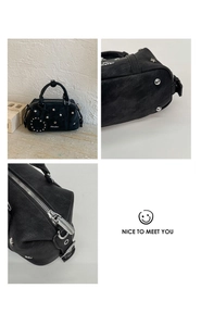 Detail view of black pebbled leather Boston bag with star studs and silver hardware
