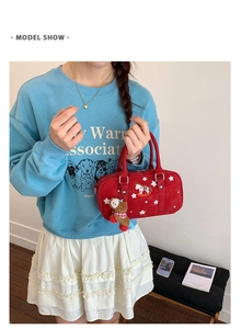 Close-up of red Boston bag featuring star prints, horse patch, and cute bear charm