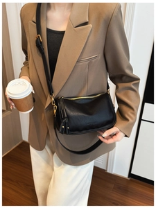 Detail of black leather shoulder bag featuring gold zipper and stylish tassel charm
