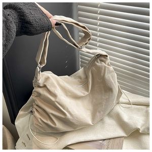 Détail du sac dumpling en nylon beige avec bandoulière réglable et boucles métalliques