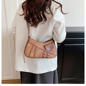 Detail view of brown vintage punk shoulder bag with rivets on a white blazer model