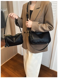 Detail view of the black leather shoulder bag showing two sizes and gold metal zipper detail