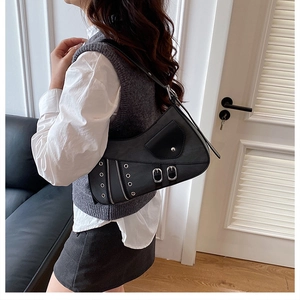 Detail of a black saddle shoulder bag with punk metal eyelets and decorative buckles