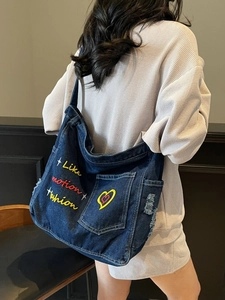 Large blue denim tote bag with colorful embroidery and distressed edges for daily commute