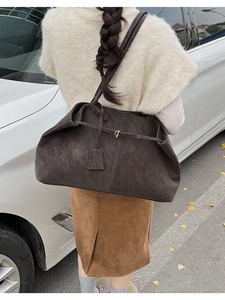 Détail d'un grand sac cabas en daim marron foncé avec boucle dorée et bandoulière longue