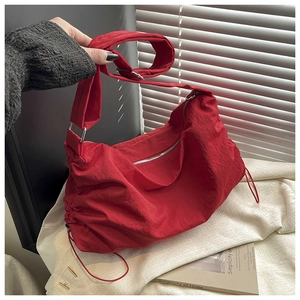Détails du sac dumpling en nylon rouge plissé avec large bandoulière et cordons de serrage